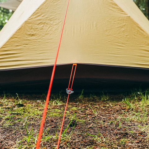 Paracord 175 Lightweight Visible Guyline For Tents And Tarps Reflective Orange 100 Ft Camping Cord shown securing a tent