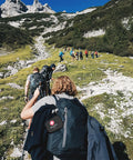 Group hiking on a mountain trail with Mini First Aid Kit 120 Piece Waterproof Hard Shell Medical Kit attached to a backpack.