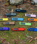 Various colored Rockband Bicycle Gear Carrier Straps including orange, laid out on grass, featuring no drop mount design.