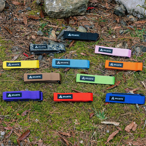 Various colored Rockband Bicycle Gear Carrier Straps including orange, laid out on grass, featuring no drop mount design.