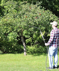 Person using Farm Grade Adjustable Spray Gun With 50 Inch Reach, 18 Orifice, in garden on apple tree with 3 Eighth Inch Inlet.