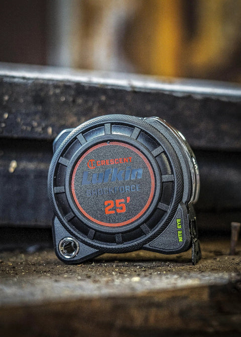1-3/16 Inch By 25 Foot Dual Sided Tape Measure With Nite Eye Glow resting vertically on a wooden surface