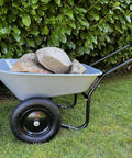 Two Wheel Poly Tray Wheelbarrow With Air Filled Tires, 5 Cubic Foot Rust Proof Tray, 300 Lb Load Capacity filled with rocks