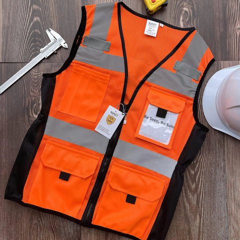 Womens Slim Fit Reflective Safety Vest With 11 Spacious Pockets Breathable Mesh High Vis Orange Work Gear Built Hella Comfy For Hectic Job Sites Flexible Waistband For Smooth Movement And Solid All Day Visibility on wooden surface with tools.