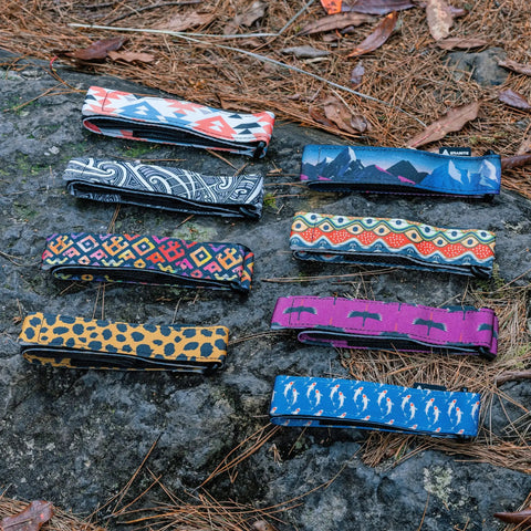 Assorted colorful Rockband Frame Carrying Strap for Inner Tubes and Bike Tools displayed on rocks, no backpack needed.