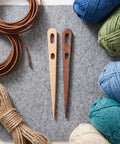 8-Piece Wooden Big Eye Knitting Needles With Double Eye Design And Smooth Rounded Tips For Wool And Nylon Crafts, Ideal For Scarves Macramé Tapestry And Crochet Projects For Yarn Lovers. Two wooden needles with yarn skeins.