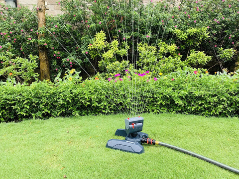 Adjustable 4 Way Mini Turbo Oscillating Sprinkler With Quick Connect Starter Set on lawn, spraying water over grass