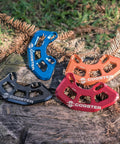Four colorful Cogster bash guards on a log, including black FortiGuard Alloy MTB Bash Guard ISCG05 Compatible For 26T To 36T Chainrings.