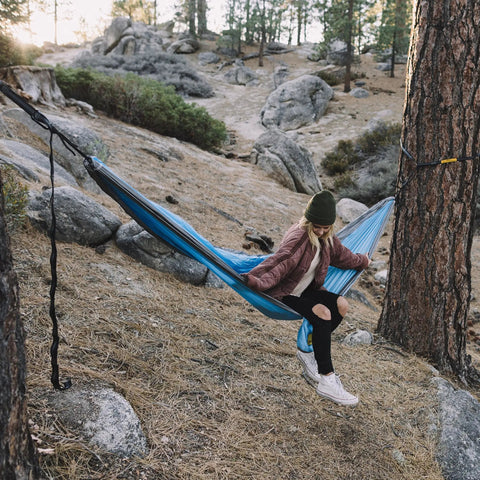 Person sitting on hammock with heavy duty hammock straps for trees 10 foot kit with carabiners and 38 loops setup between trees.