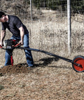 1-Man Earth Auger Powerhead With Sidekick Auger Torque Reducer For One-Man Operation in action, digging soil in a rural setting