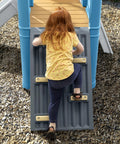Child climbing on vintage style outdoor kids playset with climber and slide for backyard adventures featuring a climbing wall.