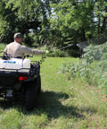 15 Gallon ATV Boomless Broadcast Sprayer With 16 Foot Swath mounted on ATV in field, user spraying foliage