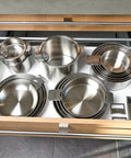 Open drawer with PSX Strate Handle Set For Cookware, removable oven-safe stainless steel handles, and stackable pans.