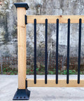 Beefy 32 And A Quarter Inch Heavy Duty Flat Straight Iron Deck Balusters in matte black facemounted on wood railing outdoors.