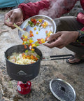 2.5 Liter Nonstick Ceramic Camp Pot For Solo Cooking With Fusion Ceramic Coating in use outdoors, stirring ingredients