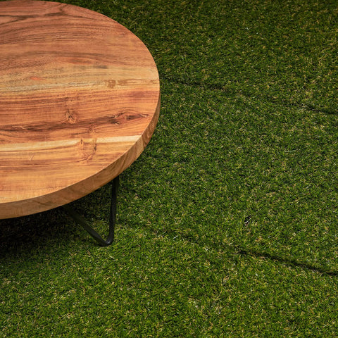 Close-up of wooden table on Interlocking Artificial Grass Tiles For Outdoor Decking And Indoor Decor Soft Synthetic Turf.
