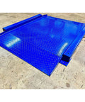 Heavy Duty Low Profile Drum Scale Built Tough With Smooth Hinged Ramps For No Sweat Barrel Rolling And Rock Solid Weighing Capability Up To 5000 Pounds With Spot On One Pound Accuracy NTEP Approved blue steel platform with diamond plate texture.