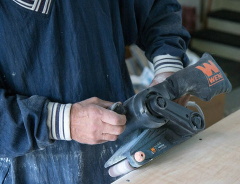 Person using Go-To Corded Belt Sander With Dust Bag, 7 Amp Motor, 3 Inch By 21 Inch Belt, Lightweight Six Pound Body on wood surface