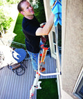 Person using Wing Span Wall Standoff Ladder Accessory for Aluminum and Fiberglass Articulating Ladders to clean windows