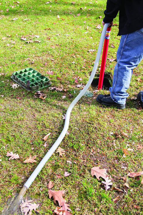 Person using Siphon King 24 Inch Hand Transfer Pump With 36 Inch Hose for water removal on grass terrain