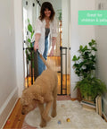 Woman opening Extra Tall Walk Through Baby Gate For Doorways And Stairs Fits Openings From 28.5 To 48 Inches 36 Inch Tall Black Metal Safety Gate No Drill Pressure Mount Ideal For Babies And Pets At Home with a dog walking through.