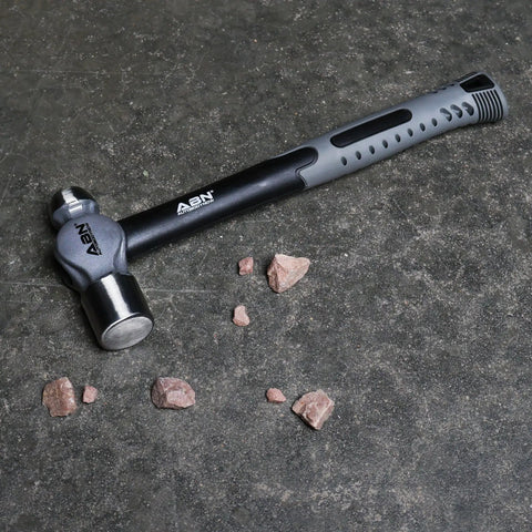 Ball Pein Hammer Set 5 Piece Workhorse Heavy Duty For Metal Rivets Chisels And Punches 8 12 16 24 32 Oz Fiberglass And Carbon Steel Build Great For Shaping Unhardened Metal, focusing on a single hammer with rocks on concrete surface.