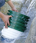 Hands rinsing 9-Piece Patented Stackable Gold Prospecting Sifting Pan Set With Stainless Steel Mesh under running water