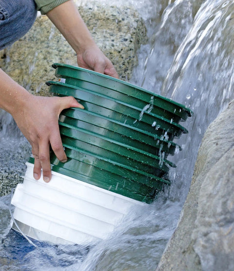 Hands rinsing 9-Piece Patented Stackable Gold Prospecting Sifting Pan Set With Stainless Steel Mesh under running water