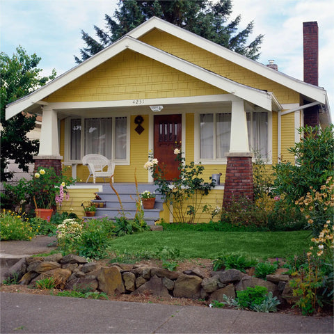 Charming yellow house with porch and garden, showcasing weatherproof outdoor lighting fixture placement.