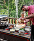 Father and daughter using Outdoor Pizza Oven On The Go For Gas Or Propane Cooking with toppings on a table outdoors