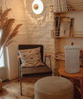 Cozy room with chair, ottoman, and Dope Freestanding Toilet Paper Storage Stand In Natural Jute Weave beside a reed basket.