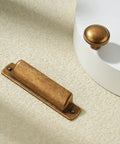 10 Pack Antique Brass Cup Pulls For Kitchen Cabinets And Furniture, 3 Inch Hole Center Drawer Pulls with a matching knob on white surface