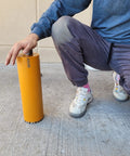 Person holding Turbo Diamond Core Drill Bit 4-1/2 Inch For Concrete And Masonry, 14 Inch Depth, with laser welded teeth on a sidewalk.
