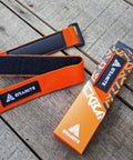 Rockband Bicycle Gear Carrier Strap in Orange No Drop Mount beside packaging on wooden surface
