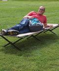 Person lounging on Trailhead II Large Folding Camping Cot With Easy Setup And Takedown, Supports Up To 300 Lbs, Stands 6 Ft 2 In Tall