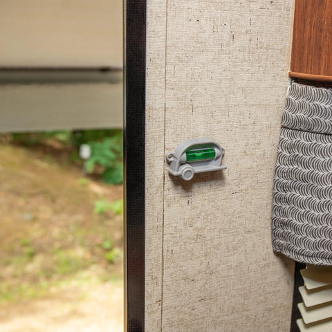 Retro RV Leveling Pack with front to back and side to side on point precision mounted on RV wall near wooded area