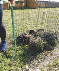 30 Inch Open Wire Mesh Compost Bin With Front Access Door For Outdoor Use set up in a garden, partially filled with compost material.