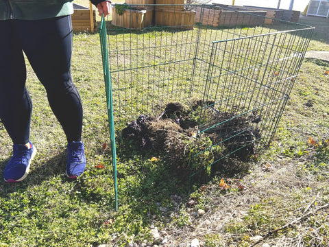 30 Inch Open Wire Mesh Compost Bin With Front Access Door For Outdoor Use set up in a garden, partially filled with compost material.