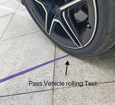 Rock Solid 1/4 Inch By 50 Foot Reinforced PU Air Hose With Swivel Quick Coupler And Male Plug Bend Restrictor Heavy Duty Pneumatic Tubing Built Tough Shop Ready Purple Finish under vehicle tire during rolling test.