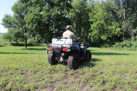 ATV mounted with 15 Gallon ATV Boomless Broadcast Sprayer With 16 Foot Swath, 2.2 GPM On Demand Diaphragm Pump in use on field