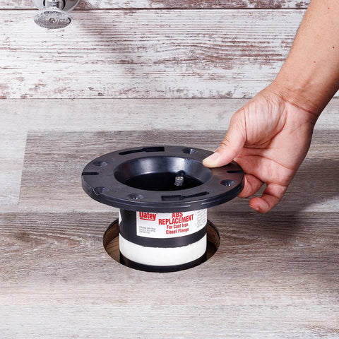 4-Inch ABS Cast Iron Closet Flange Replacement with Rubber Gasket and Stainless Steel Bolts being installed by hand