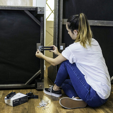 Woman installing Heavy Duty Steel Couch Clamps Keep Your Section Locked Down Adjustable Non Slip Sofa Connectors under a sectional.