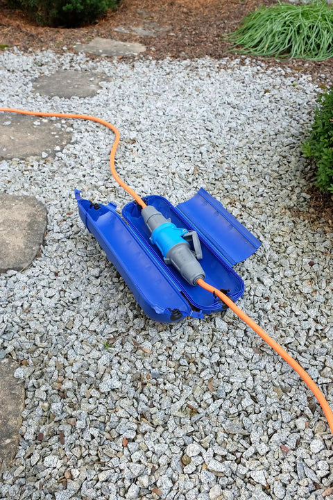Outdoor IP44 Protected Power Box For 230V Extension Cables, open on gravel, shown with orange cable connector.