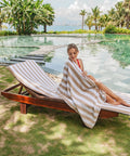 Two Pack California Style Chaise Lounge Cover Towels With Pockets Striped 100 Percent Cotton Cabana Covers for Beach Pool Outdoor Chairs 30 By 85 Inches Beige shown poolside with striped beige and white pattern