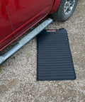 VersaMat Roll Up Workhorse High Density Foam Utility Mat Black in use beside a car on gravel surface