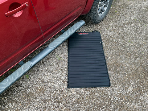 VersaMat Roll Up Workhorse High Density Foam Utility Mat Black in use beside a car on gravel surface