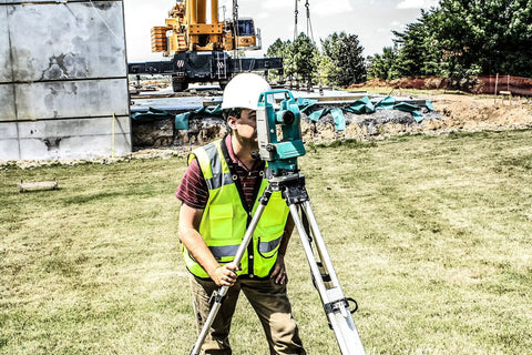 Professional Grade High Visibility Safety Vest Class 2 Reflective Trim Heavy Duty Construction Workwear For Outdoor Crews Safety Green Medium worn by a surveyor using a level.