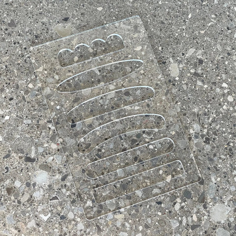 Six In One Charcuterie Board Handle Template Acrylic Router Guide showing clear acrylic with grip profiles on a concrete surface.