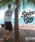 Person wearing Women's V Neck UPF 50 Plus Long Sleeve Sun Shield Tee Built For Outdoor Performance, standing by a palm tree by the sea.
