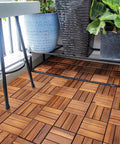 Teak Interlocking Patio Deck Tiles Set of 10 12 Inch by 12 Inch Outdoor Wood Flooring Mats on balcony with plants and table.